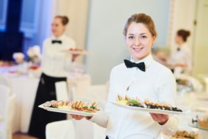 fine dining event venue with draped tables and professional servers holding platters