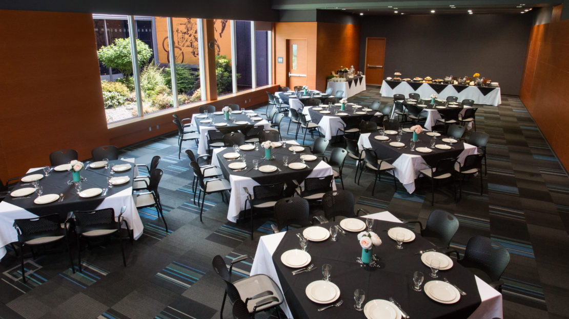 event venue and meeting space showing square tables and chairs set for dining.