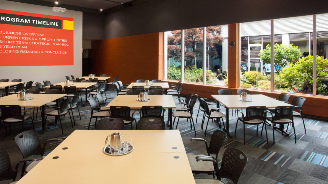 event venue and meeting space showing square tables and chairs with water pitchers, set for business meeting