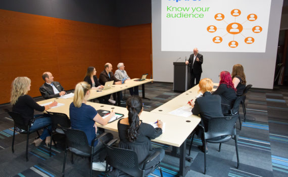 Meeting space with tables, chairs, podium & active presentation