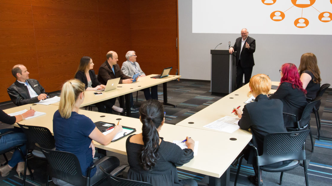 Meeting space with tables, chairs, podium & active presentation