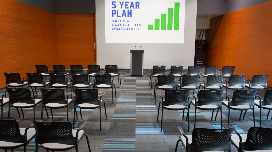 event venue and meeting space showing podium and auditorium seating and projection display for business meeting