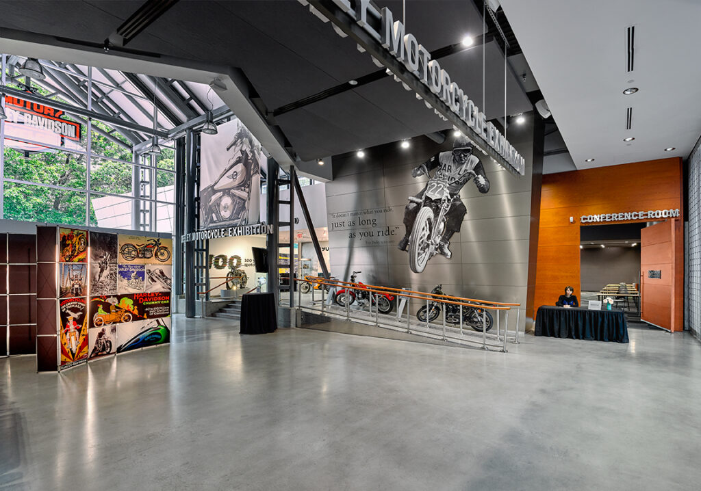 The image shows the foyer with a modern design and a registration table in the entrance of the conference room